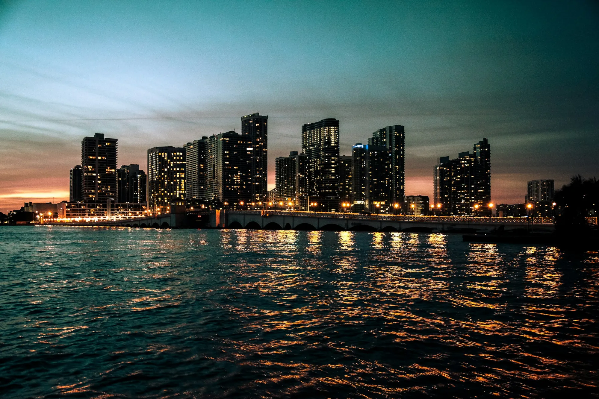 The downtown Miami skyline lit up at dusk across the water