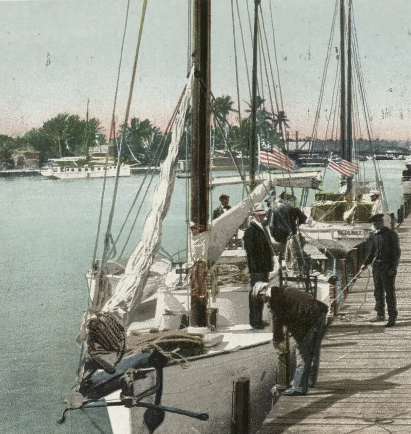 A 1905 postcard - sailing boats tied up at a dock on the Miami River, men at work on deck