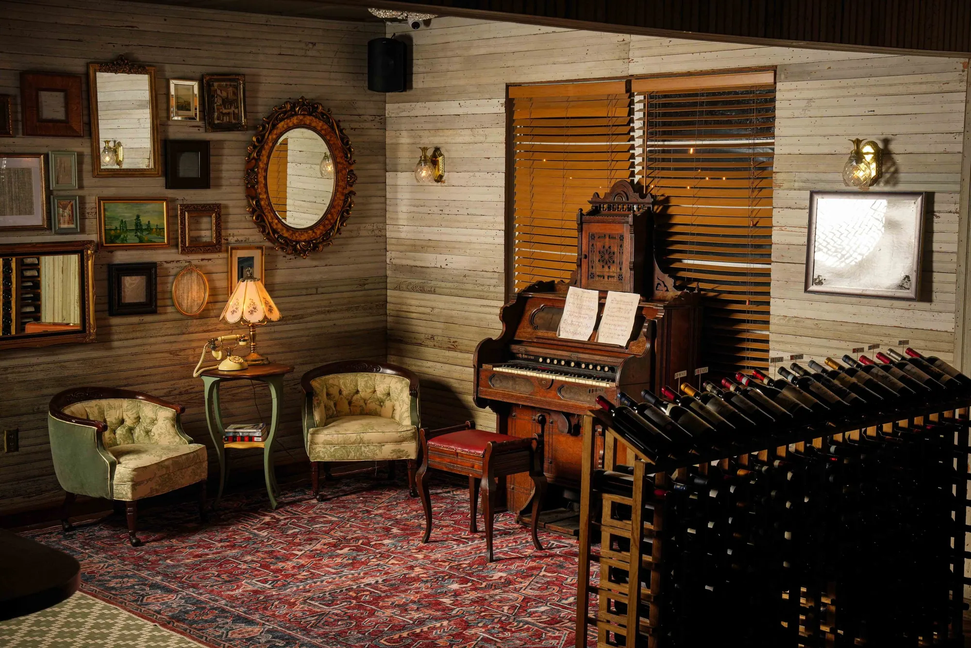 The parlour - a pump organ, antique chairs and framed mirrors on timber walls