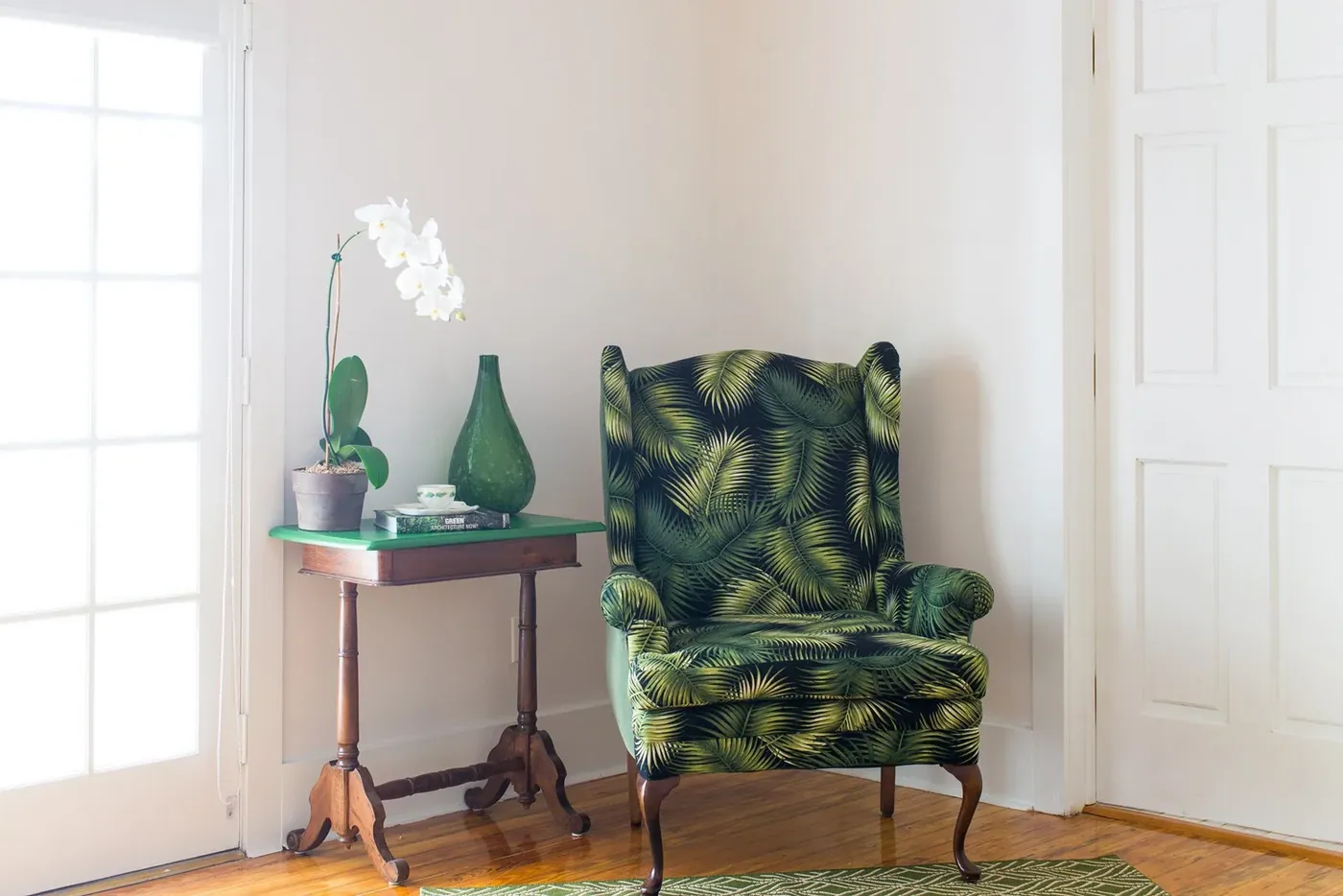 Green wingback chair in a corner of a guest room