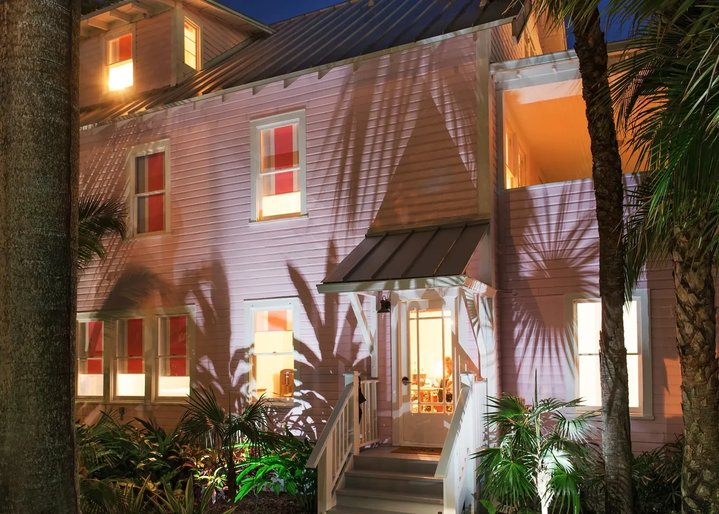 The pink house and the garden lit warmly after dark