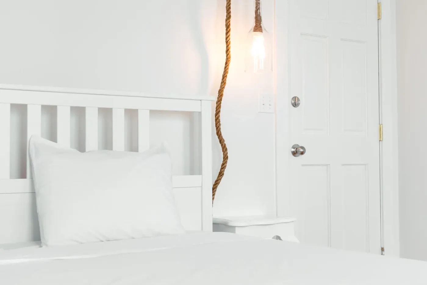 White guest room with tall sash windows and simple furnishings
