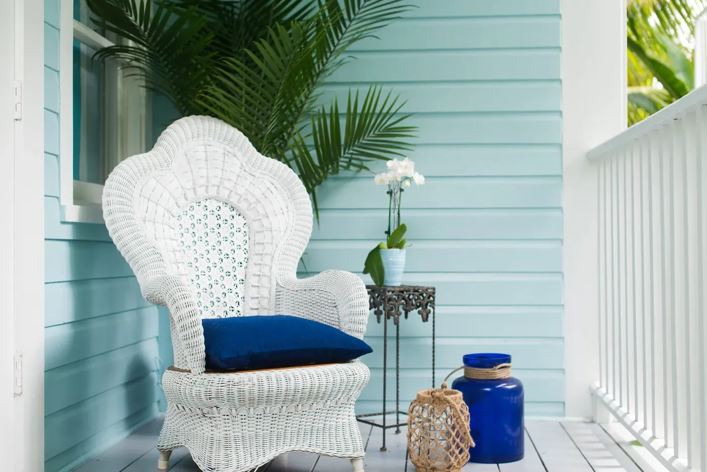 Wicker chair on a cottage veranda beside a louvred window